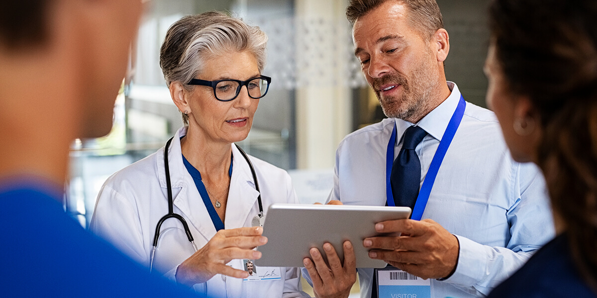 Two physicians looking over medical documents in front of a man and woman